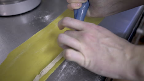 pasta filling being piped onto a sheet of rolled dough