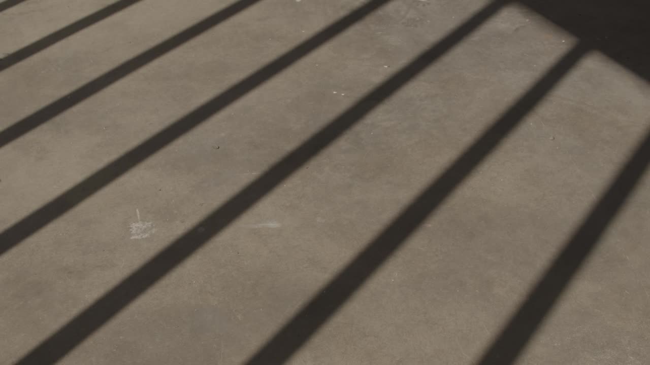 콘크리트 위로 감옥 바의 움직이는 그림자