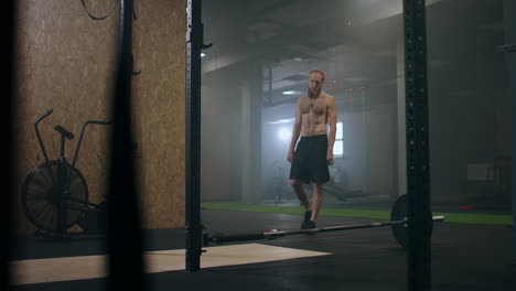 a male athlete lifts a weight bar with one hand in slow motion. strength training for a boxer. the man is sweating working out in the gym practicing the force of the blow with his hand