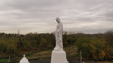 an aerial view of a statue of the virgin mary on top of a catholic church in upstate, ny