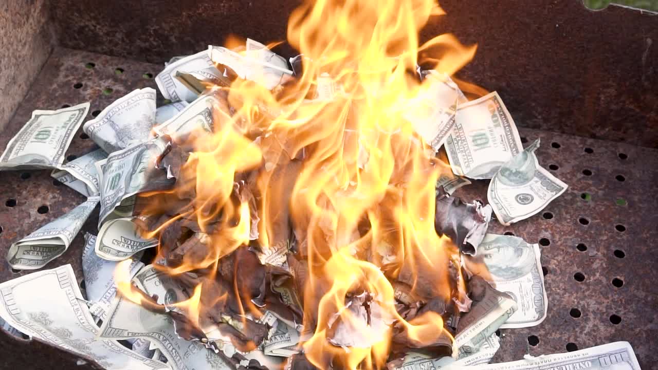 Fake dollars are on fire. Burning counterfeit money in the grill. Concept of crisis, loss, recession or failure