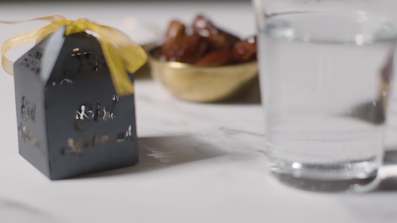 이드 축제를 기념하는 대리석 배경에 물 한 잔과 선물 상자가 담긴 날짜 그릇