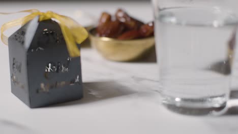 bowl of dates with glass of water and gift boxes on marble background celebrating festival of eid