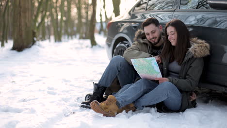 pareja caucásica sentada en la nieve y descansando durante un viaje por carretera.