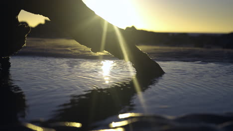 enge statische aufnahme des sonnenaufgangs mit treibholz und pfütze am strand