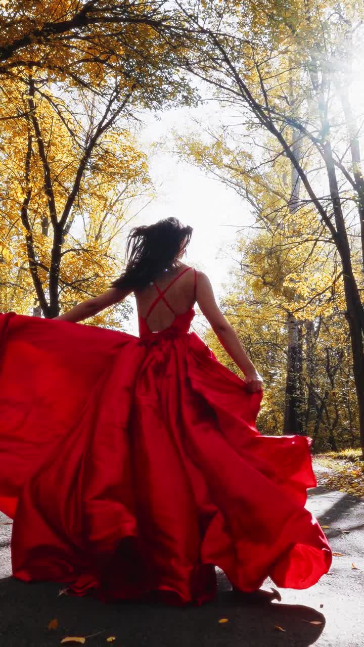 A Enchanting Moment in Autumn: A Woman in a Flowing Red Dress Captures the Beauty of Fall Amidst Golden Foliage in a Magical Woodland Setting