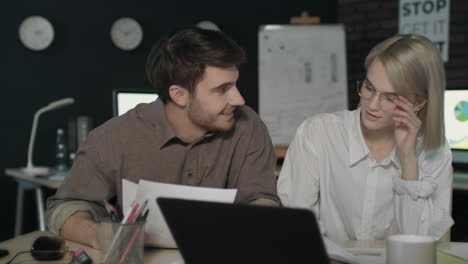 socio de negocios discutiendo informes financieros frente a la computadora portátil en la oficina nocturna