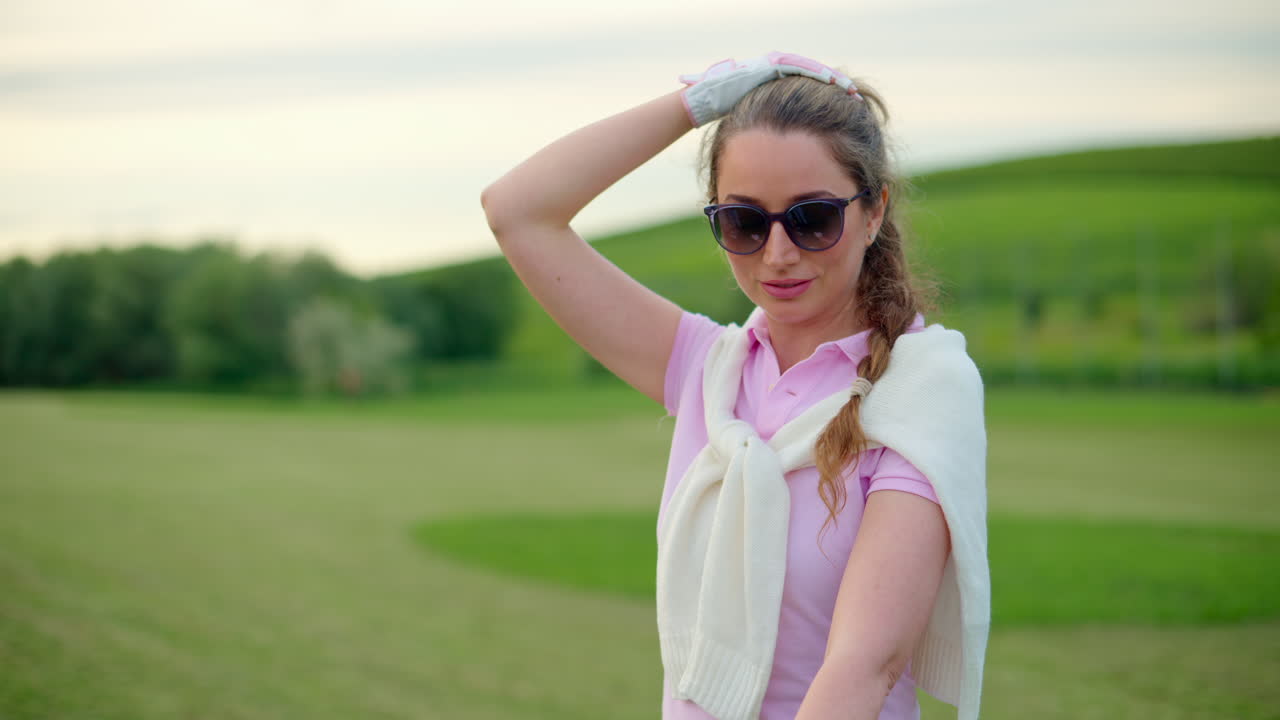 Woman dressed in white and pink standing on a field, looking around