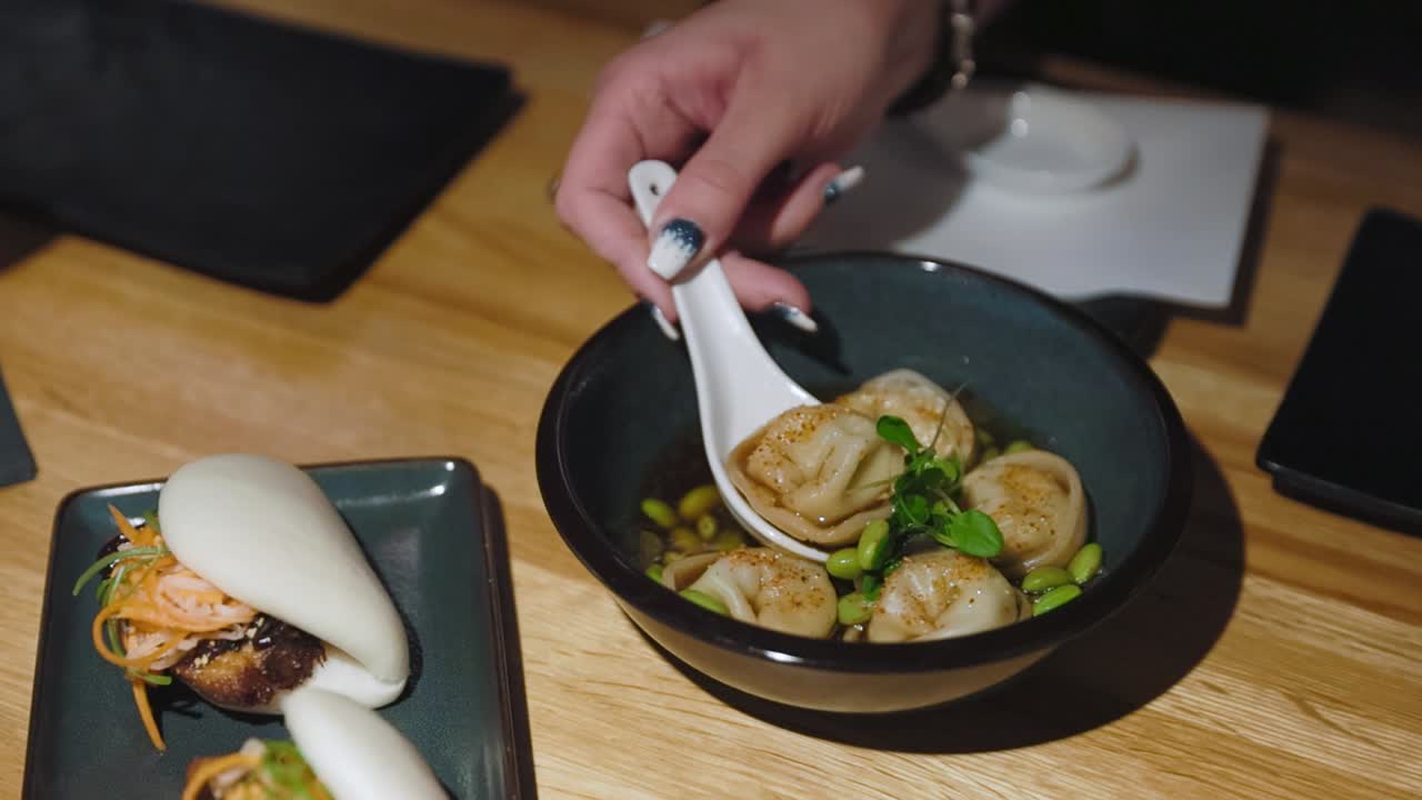 A woman grabs a scoop of dumpling soup with a spoon
