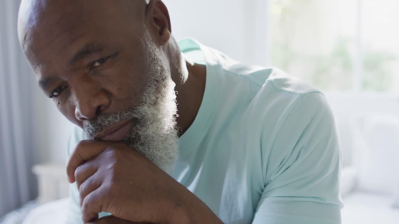 Thoughtful senior african american man in bedroom holding walking cane