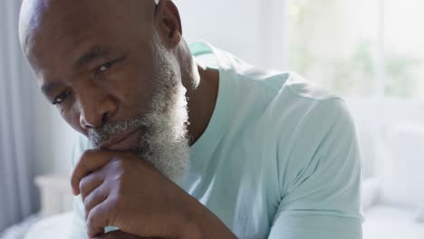 Thoughtful-senior-african-american-man-in-bedroom-holding-walking-cane