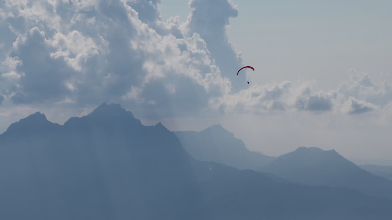 un parapente vuela sobre montañas y nubes