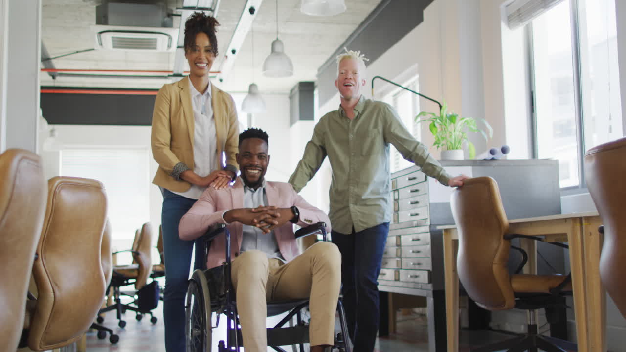 Portrait of happy diverse business people with disabled colleague in creative office
