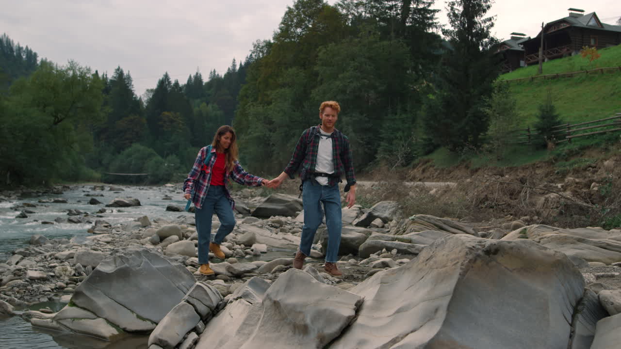 산 강을 따라 하이킹하는 커플. 강의 바위 해안에서  ⁇ 는 여행자