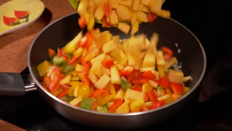 adding mixed chopped vegetables into a frying pan with browning onions