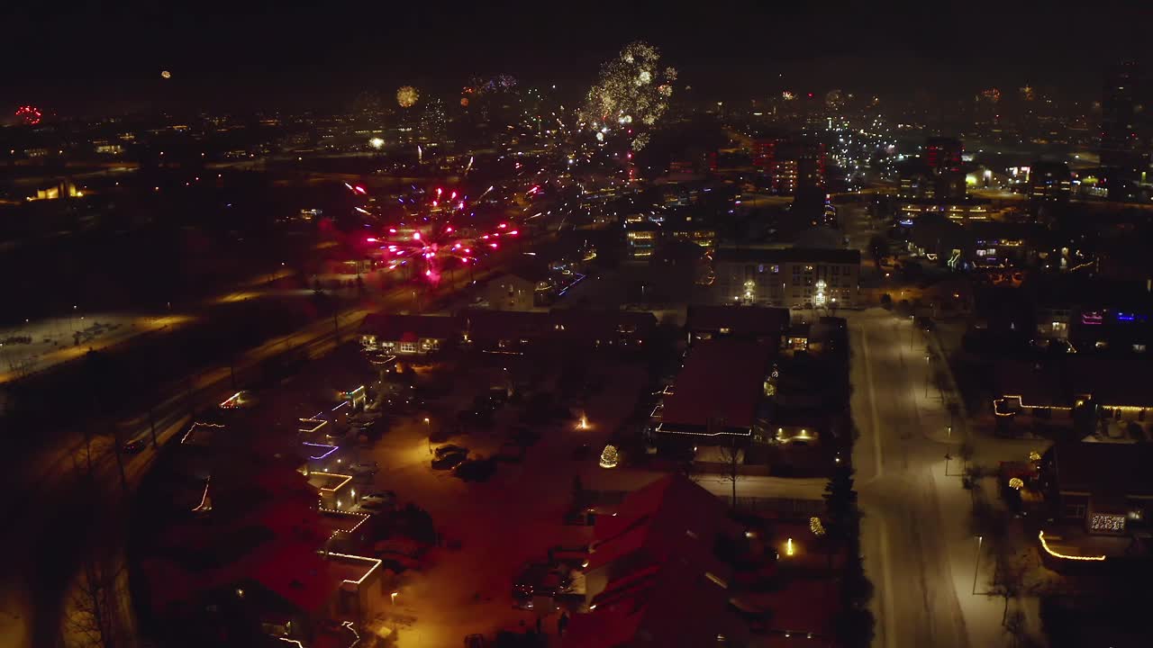 Aerial View Of Stunning Display Of New Year's Eve Fireworks Lighting Up City In Iceland On Winter Night. orbiting tilt-up shot