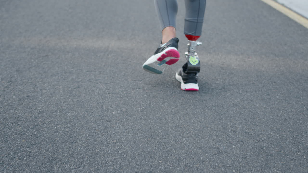 Disabled woman legs running on road. Sportswoman jogging on running surface