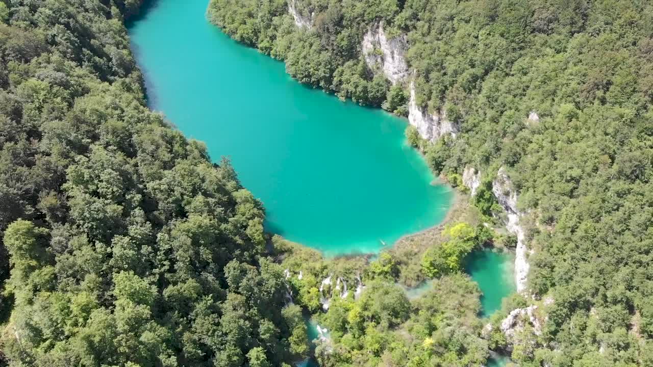 toma aérea de un valle de rocas blancas con árboles y un lago azul vivo