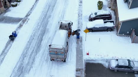 aerial shot of a garbage truck picking up trash despite the icy streets