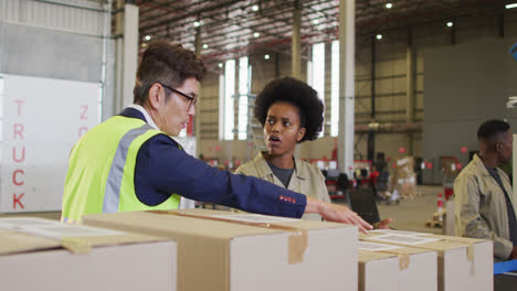 diverse male and female workers with boxes talking in warehouse