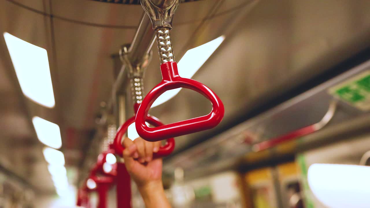 움직이는 열차에서 손잡이를 잡는 손