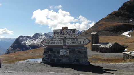 Road-sign-of-Col-de-l'Iseran-with-church-and-mountain-range-in-background,-France