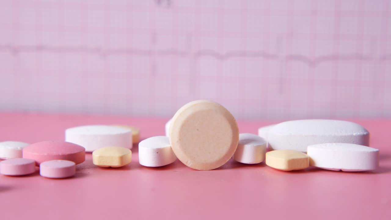 분홍색 배경에 ekg 그래프와 함께 다양한 색의 알약