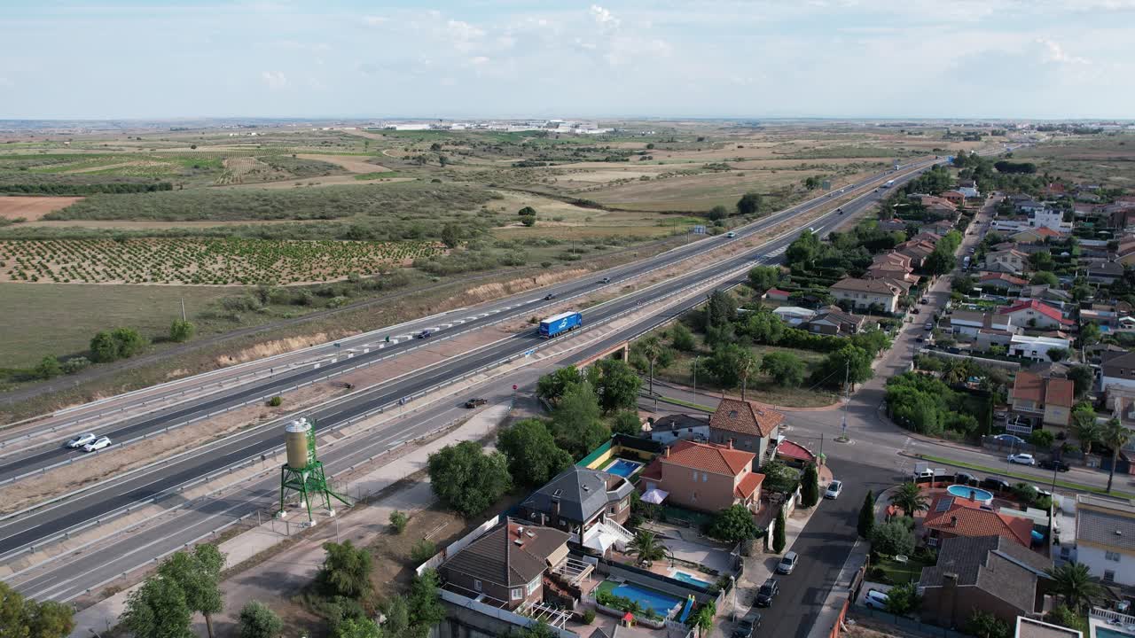 camión azul conduciendo en la autopista junto a un área residencial