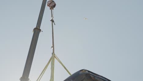 Close-up-of-a-crane-lifting-a-wrecked-an-old-car-at-the-junkyard