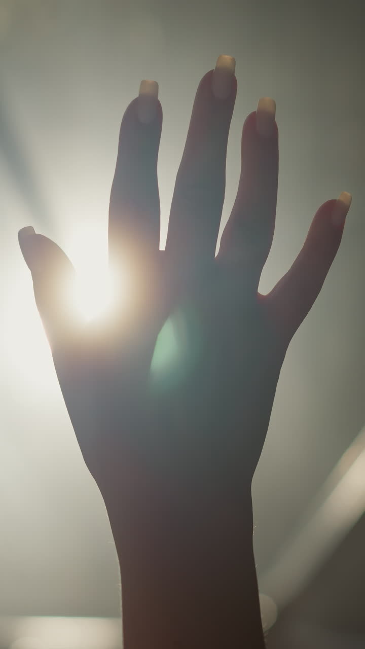 silueta de mujer en la luz de fondo en un cuarto oscuro de primer plano. mano de la dama con gestos conmovedores y luz brillante en el espacio oscuro. esperanza concepto creativo