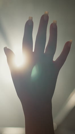 woman palm silhouette at backlight in dark room closeup. lady hand with touching gestures and glowing light in dark space. hope creative concept