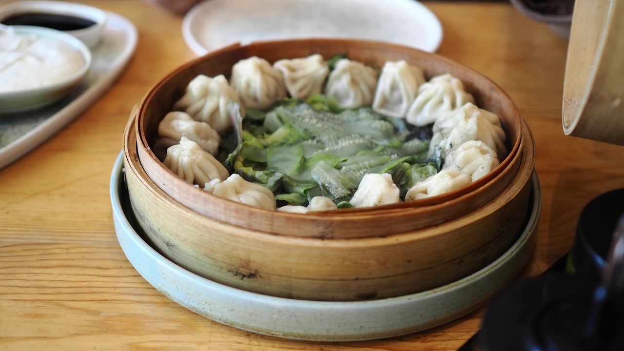 Hand Opening Bamboo Steamer Revealing Hot Steaming Dumplings