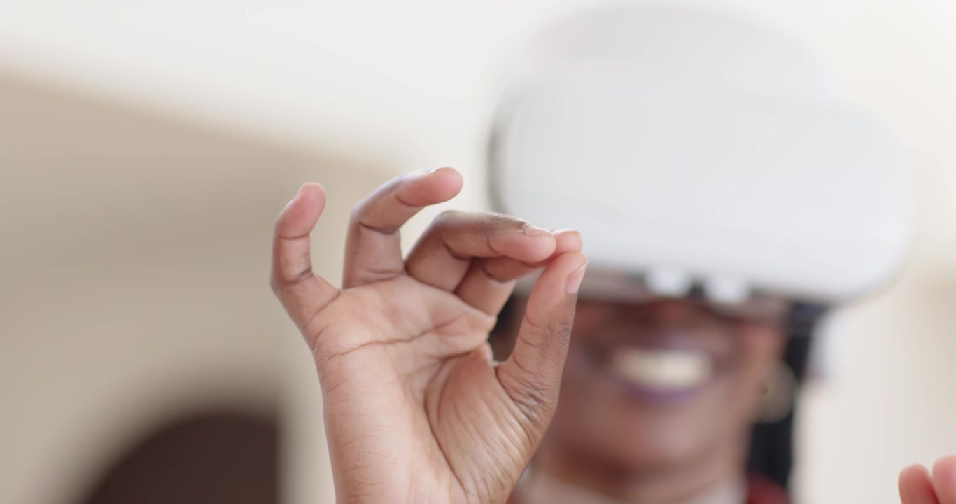Adult African American woman making pinch, open and rotate gestures via white VR headset at home