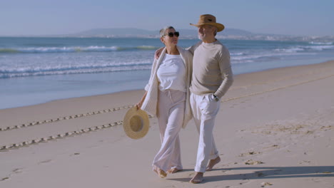 feliz pareja caucásica mayor caminando por la playa en un día soleado