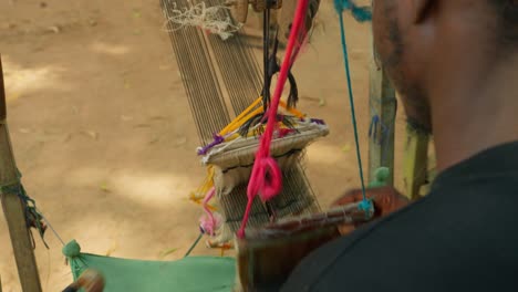 black african local man weaving kente textile by hand