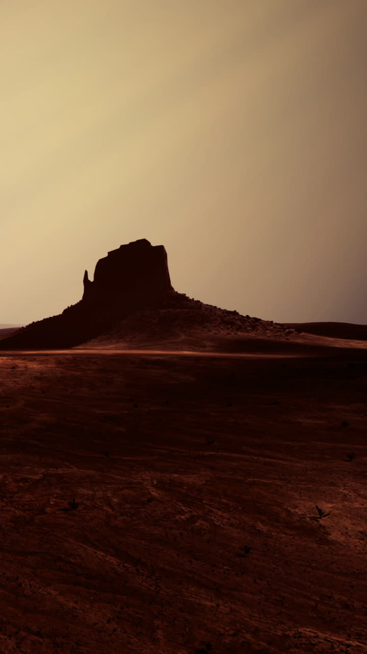 Vista di una formazione rocciosa al tramonto in un paesaggio desertico con ombre.