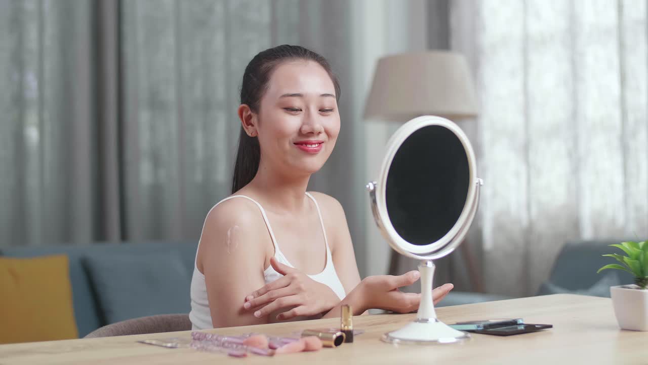 Woman Applying Makeup in Front of a Mirror