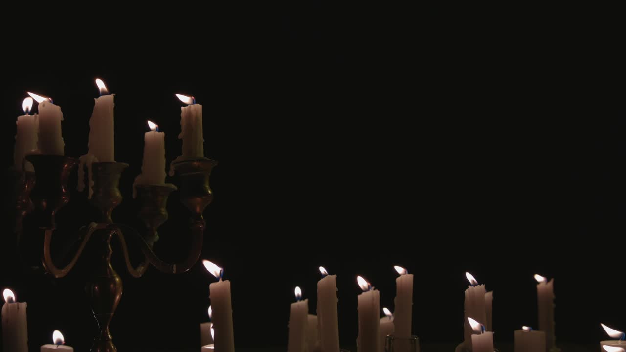 un grupo de velas blancas, algunas en un candelabro, encendidas y funcionando durante un tiempo