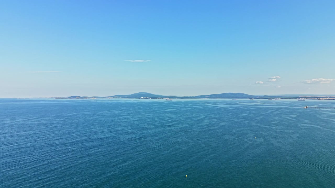 Ampia vista sull'oceano e sulla terraferma in lontananza con cielo sereno e poche nuvole durante il giorno.
