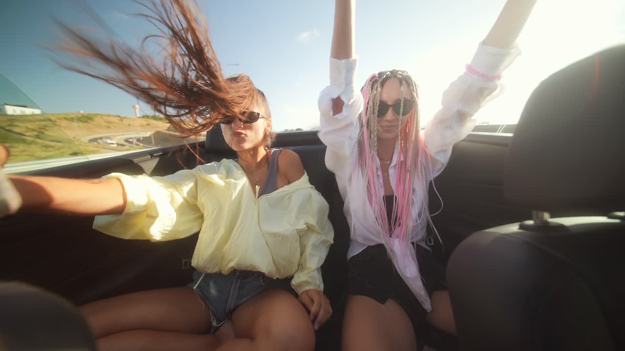 Two young women enjoying a joyful summer road trip in a convertible
