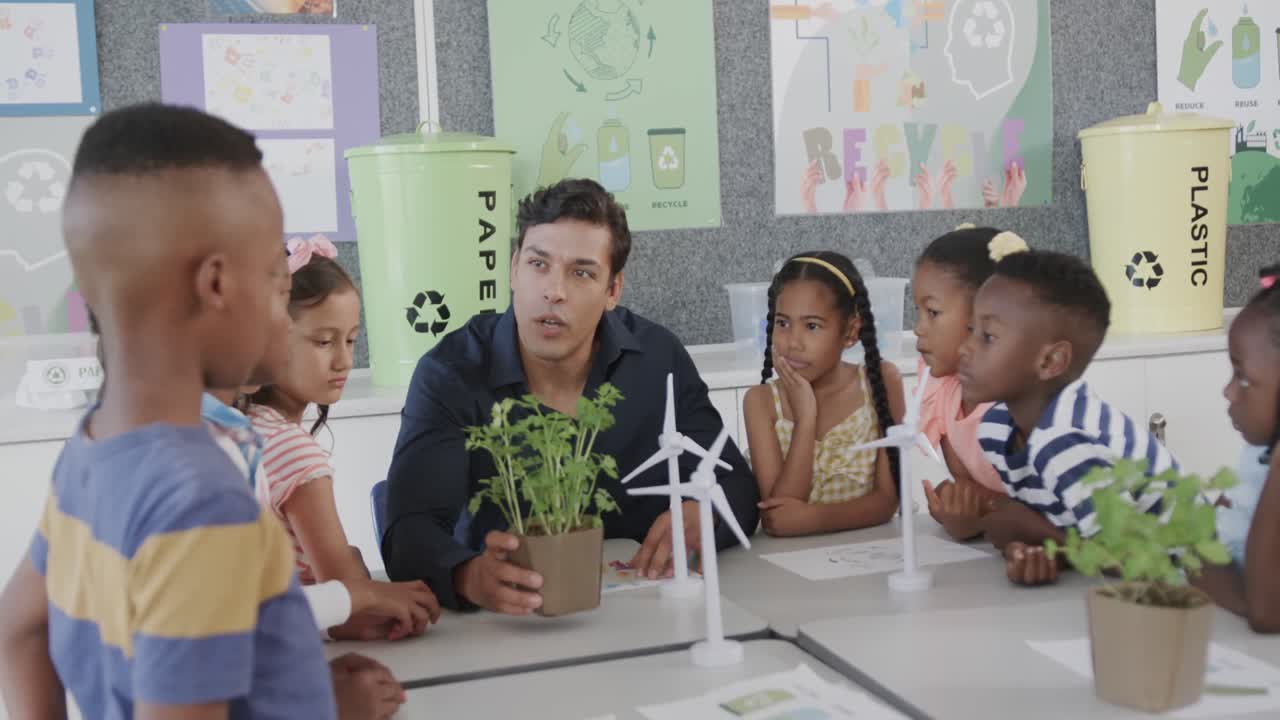 profesor masculino feliz y diverso que enseña ecología a los escolares con modelos en clase en la escuela primaria