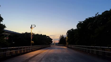 early morning light bathes an empty park bridge with trees and a warm sky