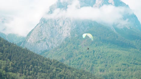 paraglider flies around in front of a beautiful mountain panorama