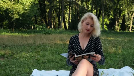 sexy girl with a big neckline sits in the park and flips through the pages