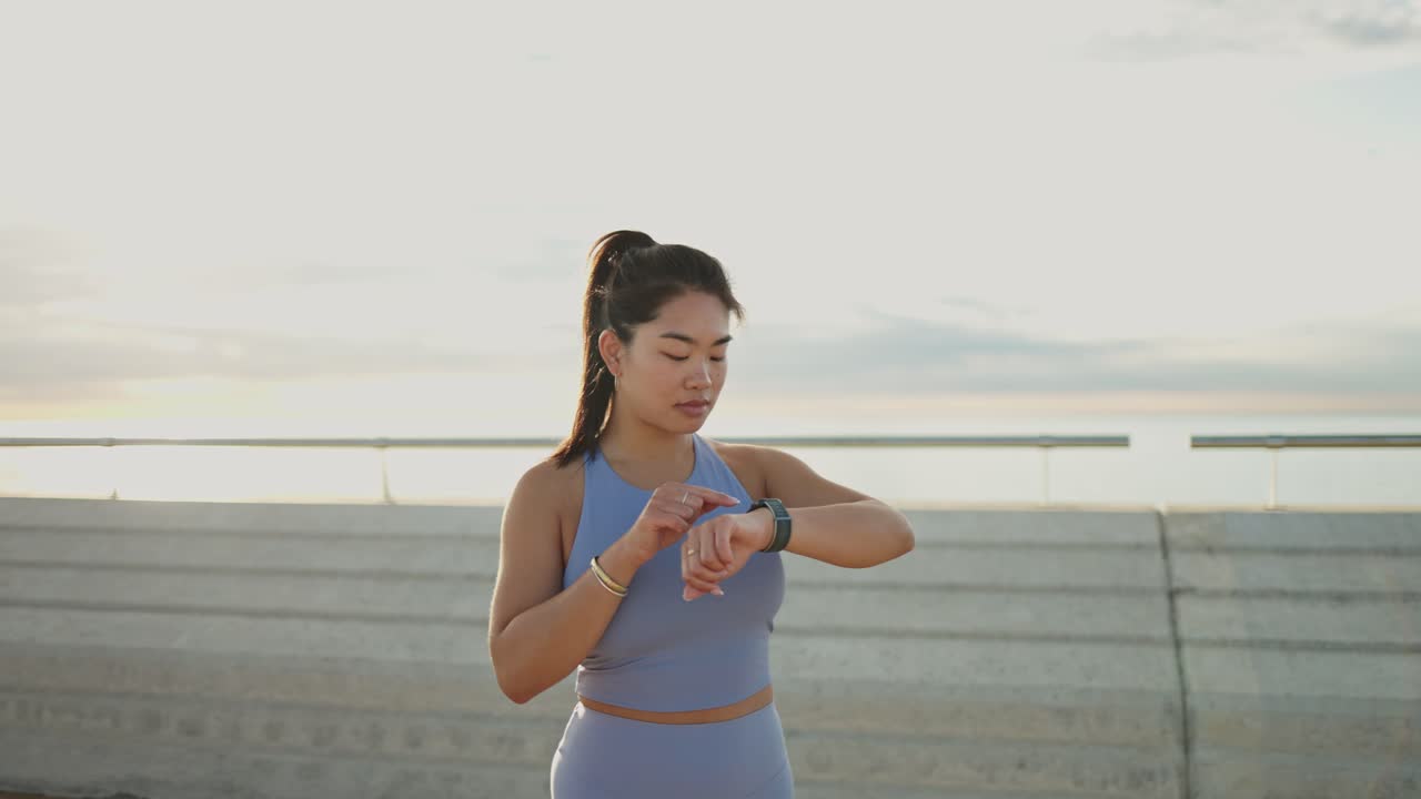 Young Asian Woman Checking Smartwatch During Outdoor Workout