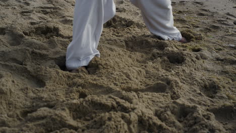 Piernas-De-Hombre-Desnudo-De-Pie-En-La-Playa-En-Primer-Plano-De-Pose-De-Karate.-Atleta-Entrenamiento-Arte-Marcial