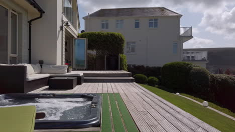 left to right pan from a beach house deck with hot tub revealing the beach in slow motion