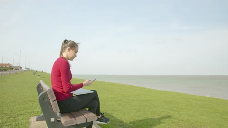 Female-turns-phone-off-and-works-on-laptop-outside-by-the-sea