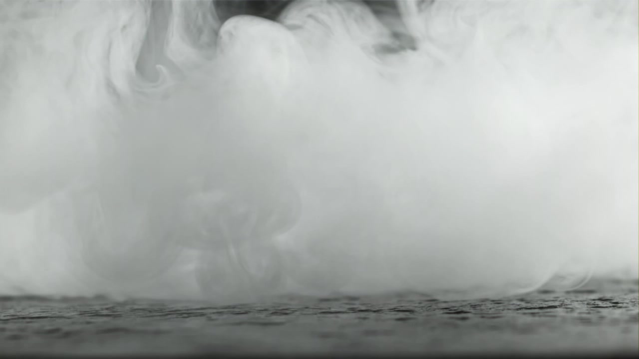 Dichter weißer Nebel breitet sich auf einem dunklen, strukturierten Boden aus