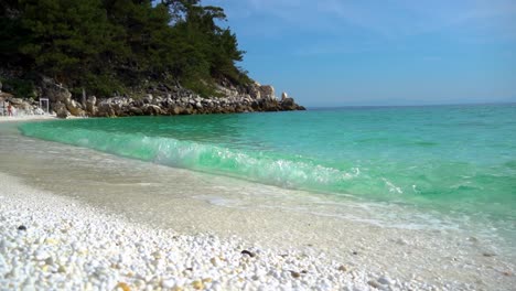 movimiento lento de las olas turquesas del mar lentamente salpicando en una playa de guijarros blancos con un cielo azul claro en el fondo, playa de mármol, isla de thassos, grecia